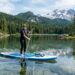 Beginner paddleboarding on a calm Oregon lake surrounded by pine trees.
